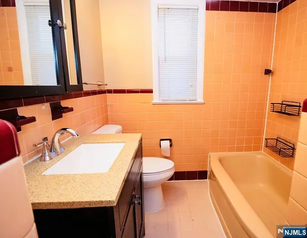 a bathroom with a granite countertop sink and a bathtub