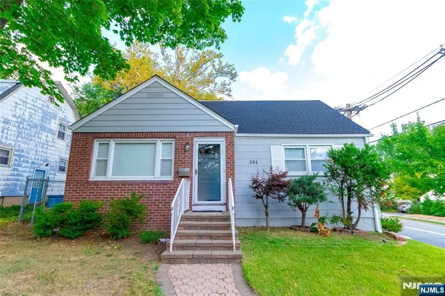 a front view of a house with a yard and green space