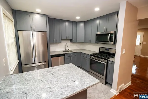 a kitchen with kitchen island stainless steel appliances cabinets a sink and a counter top space