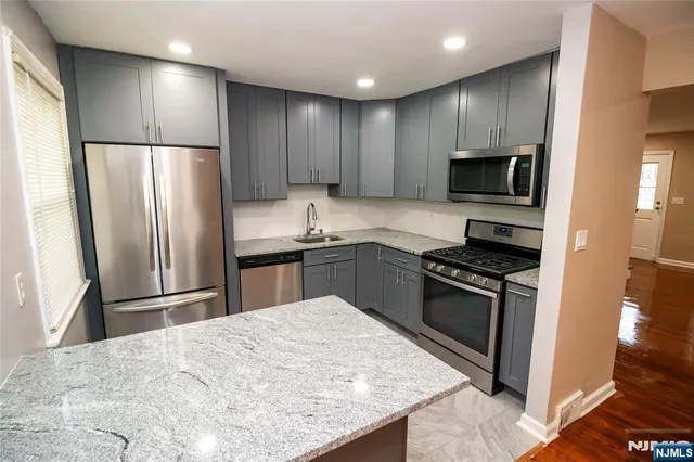 a kitchen with kitchen island stainless steel appliances cabinets a sink and a counter top space