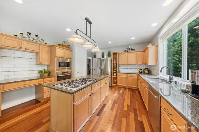 a kitchen with stainless steel appliances a stove a sink dishwasher and cabinets with wooden floor