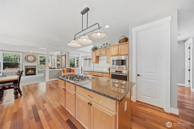a kitchen with stainless steel appliances granite countertop a sink a stove and a wooden floors