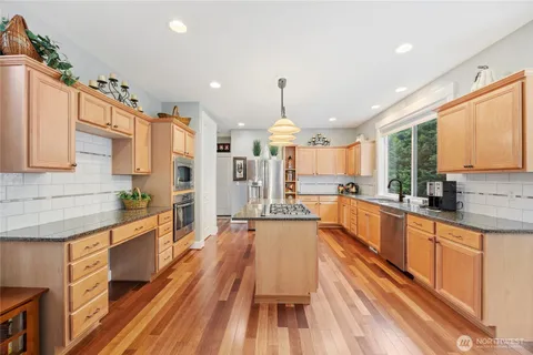 a large kitchen with granite countertop lots of counter space and wooden floor