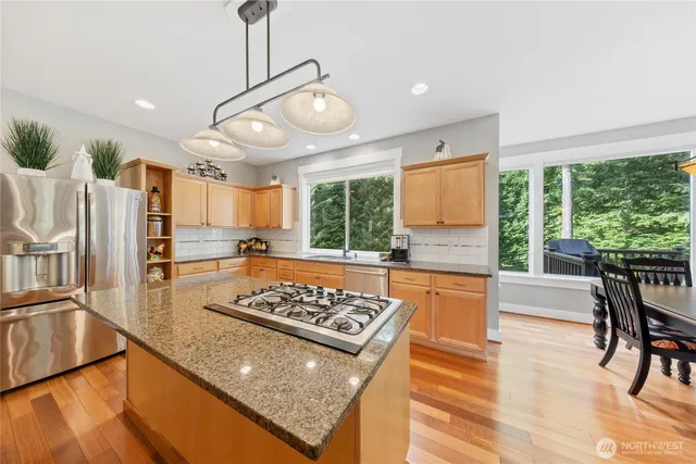 a kitchen with stainless steel appliances granite countertop a stove refrigerator and wooden floor