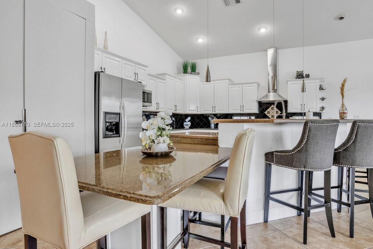 205 North 31st Avenue, Unit 1 Hollywood, FL 33021 - Photo 12 of 42 a kitchen with kitchen island granite countertop a table chairs microwave and cabinets