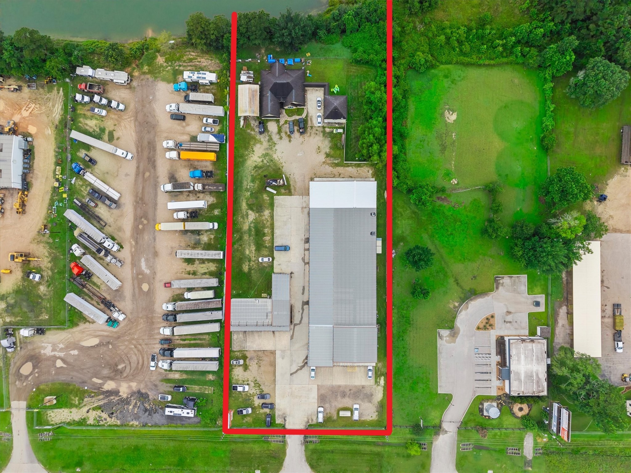 11066 Sh 242 Conroe, TX 77385 - Photo 5 of 21 This aerial photo shows a large property outlined in red, featuring a mix of open green space and several buildings. It includes paved areas and space for parking or storage, with surrounding greenery offering a blend of utility and nature.