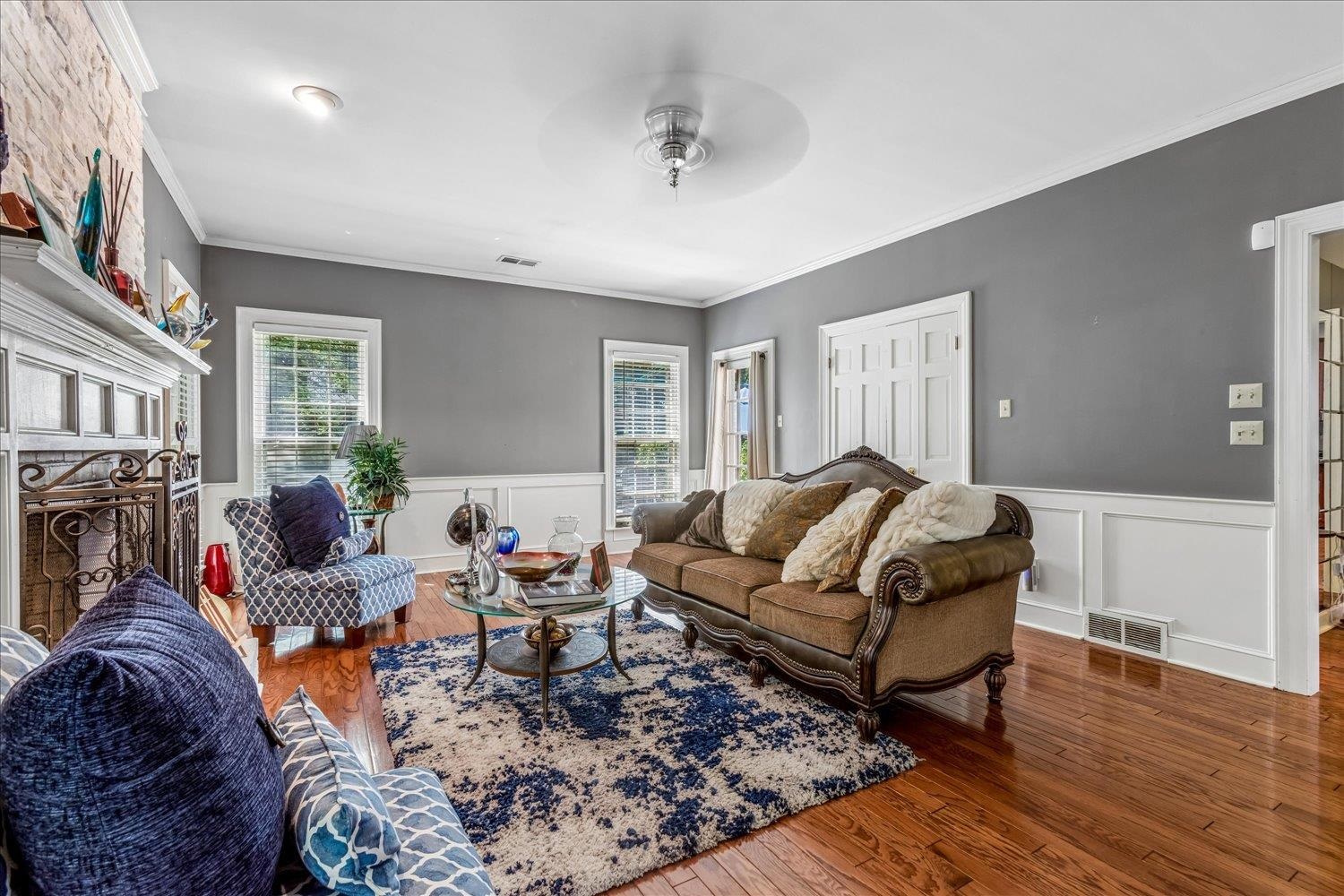 65 Summer Grove Road Memphis, TN 38018 - Photo 13 of 38 Wood-finish flooring, white wainscoting, and a stone-clad fireplace with an ornate iron screen