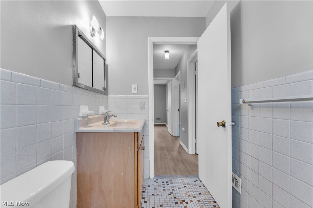 2915 Snow Road, Unit 2/UP Cleveland, OH 44134 - Photo 15 of 23 Bathroom featuring a light wood-finish vanity, wall-mounted medicine cabinet, white square tiled walls, and a multi-toned mosaic tile floor