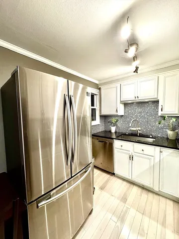 a kitchen with granite countertop stainless steel appliances a refrigerator a sink and cabinets