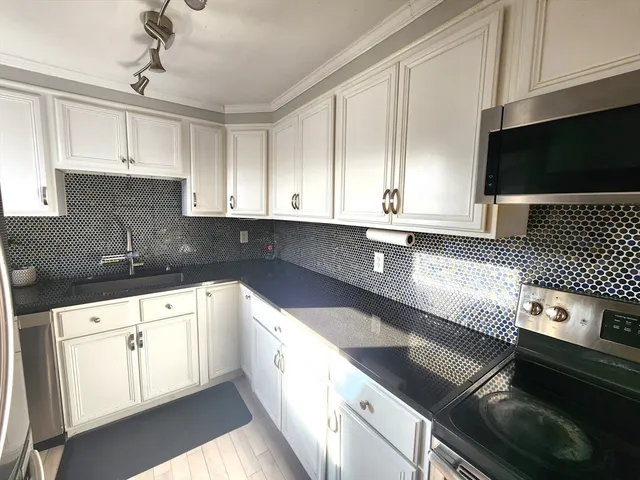 a kitchen with stainless steel appliances granite countertop a sink a stove and a microwave