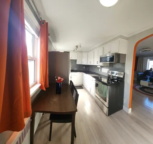 a kitchen with stainless steel appliances granite countertop a stove top oven a sink a dining table and chairs with wooden floor