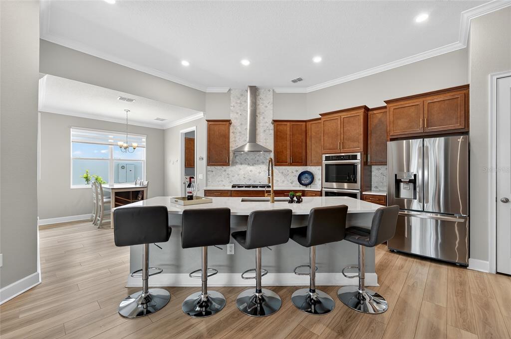 5961 Blakeney Loop Apollo Beach, FL 33572 - Photo 8 of 42 a kitchen with stainless steel appliances granite countertop a refrigerator a stove top oven and a dining table with wooden floor