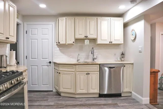 a kitchen with stainless steel appliances granite countertop a stove a sink and white cabinets with wooden floor