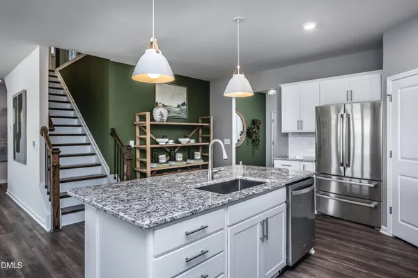 a kitchen with stainless steel appliances granite countertop a kitchen island hardwood floor sink stove and white cabinets