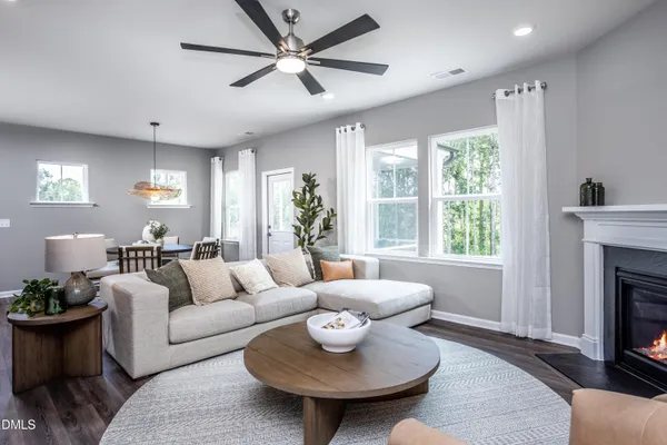 a living room with furniture kitchen view and a wooden floor