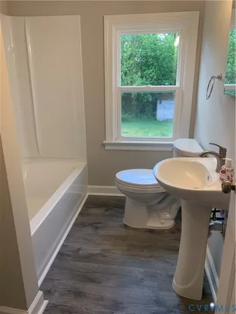 a bathroom with a sink a toilet a window and bathtub