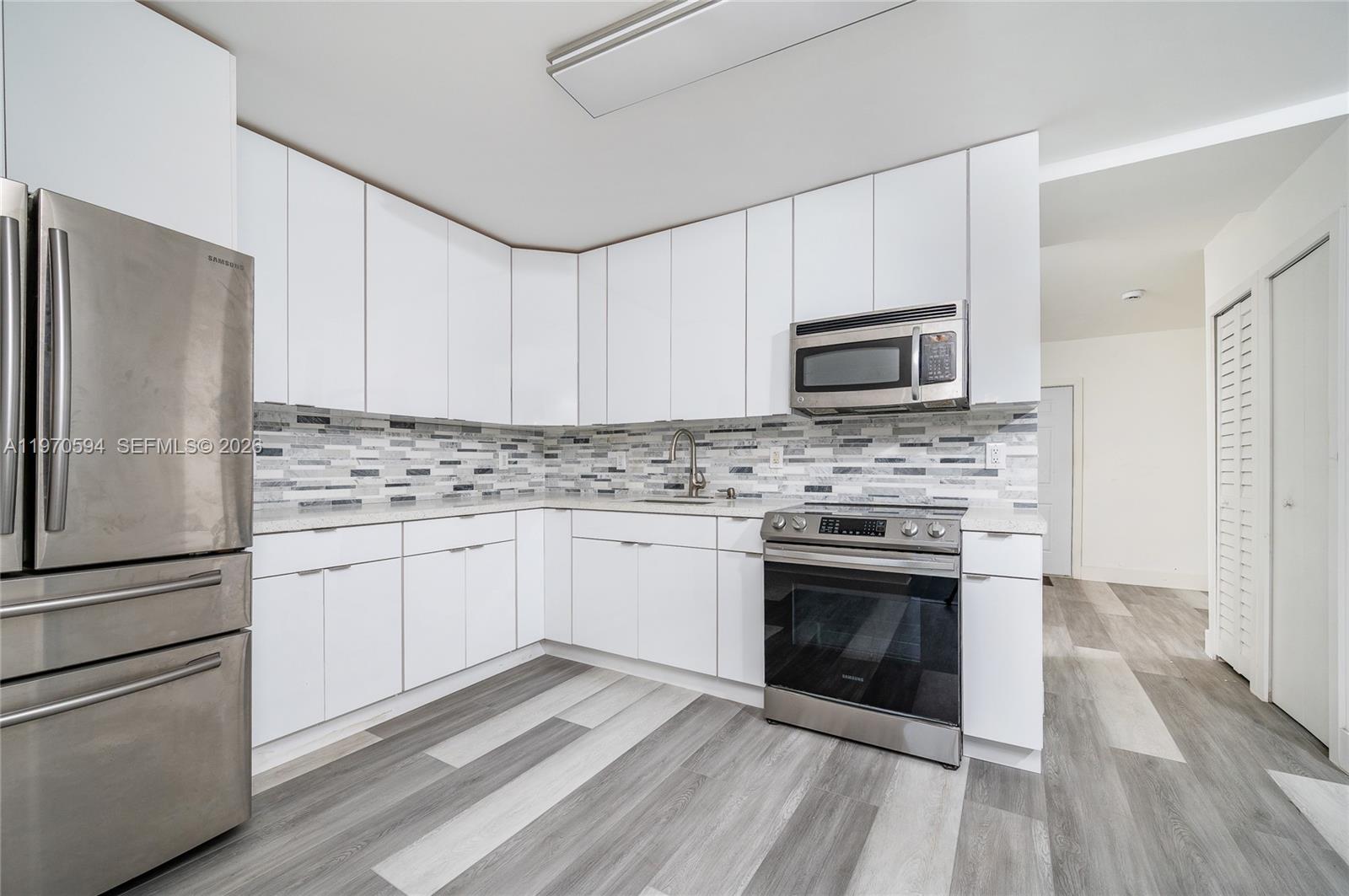 2433 Northwest 97th Street Miami, FL 33147 - Photo 28 of 41 a kitchen with granite countertop white cabinets stainless steel appliances and a wooden floor