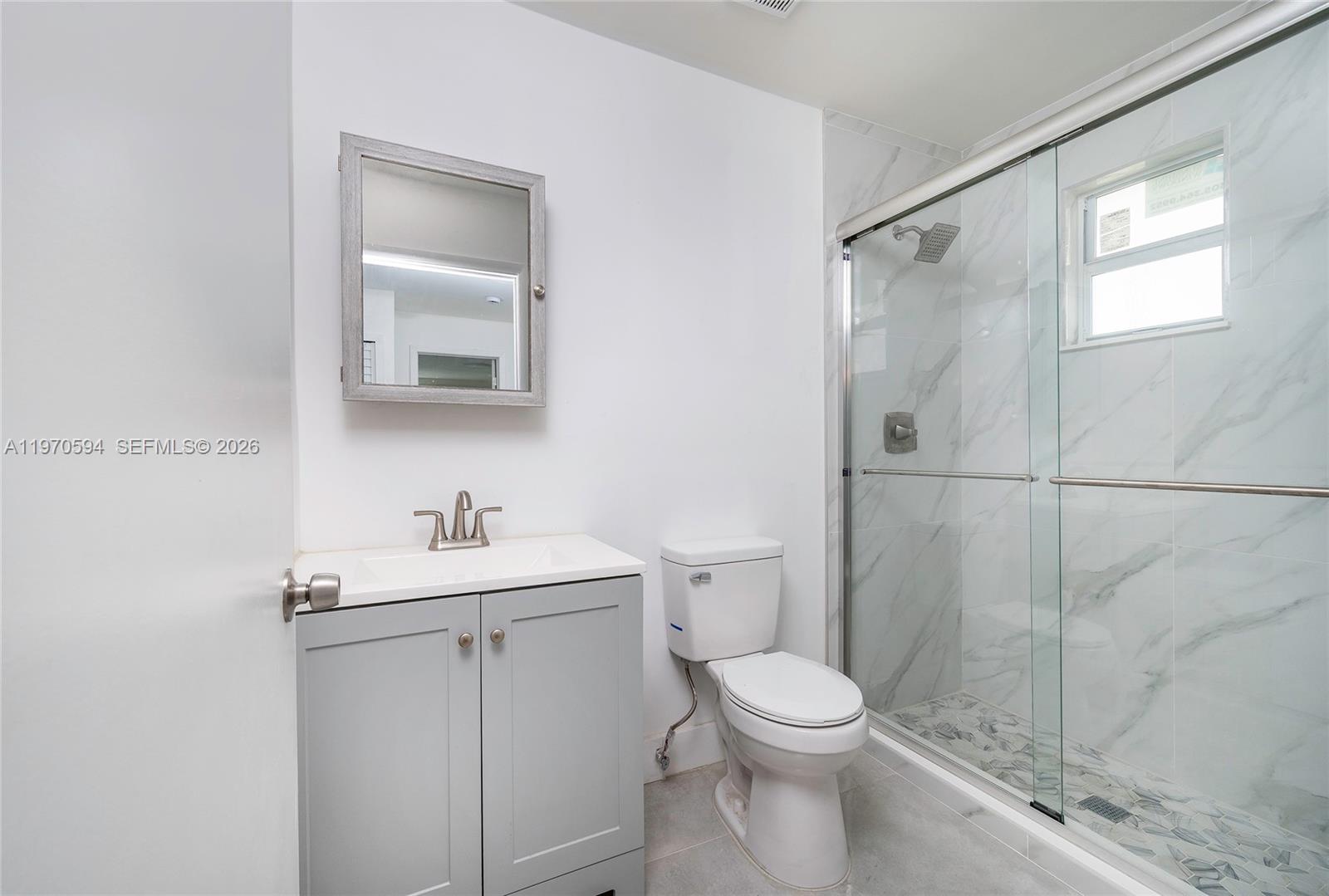 2433 Northwest 97th Street Miami, FL 33147 - Photo 34 of 41 a bathroom with a toilet sink vanity and shower