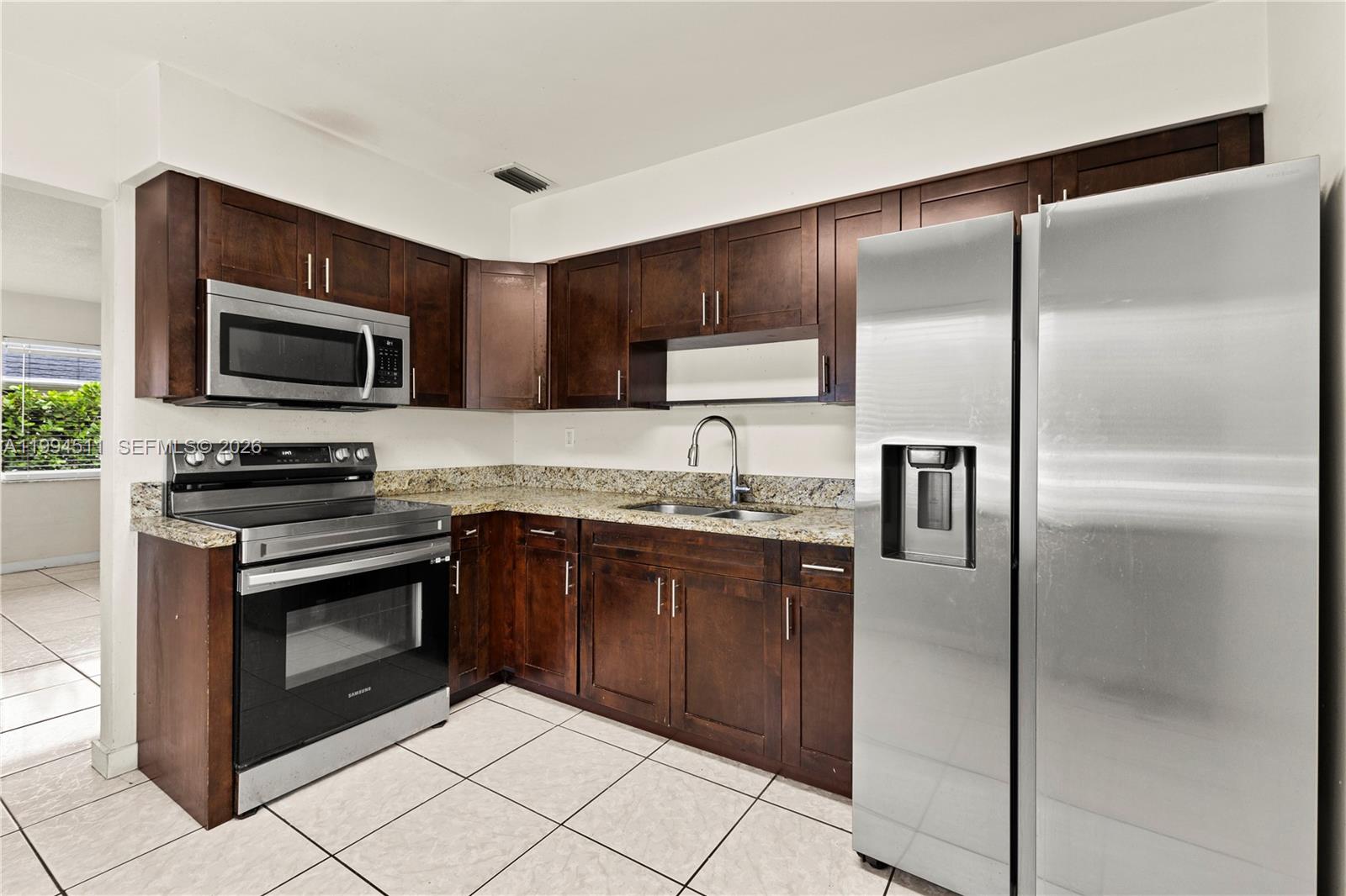 6121 Southwest 40th Court, Unit A Miramar, FL 33023 - Photo 5 of 12 a kitchen with granite countertop a refrigerator and a stove top oven