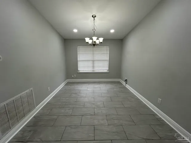 en empty room with windows and chandelier