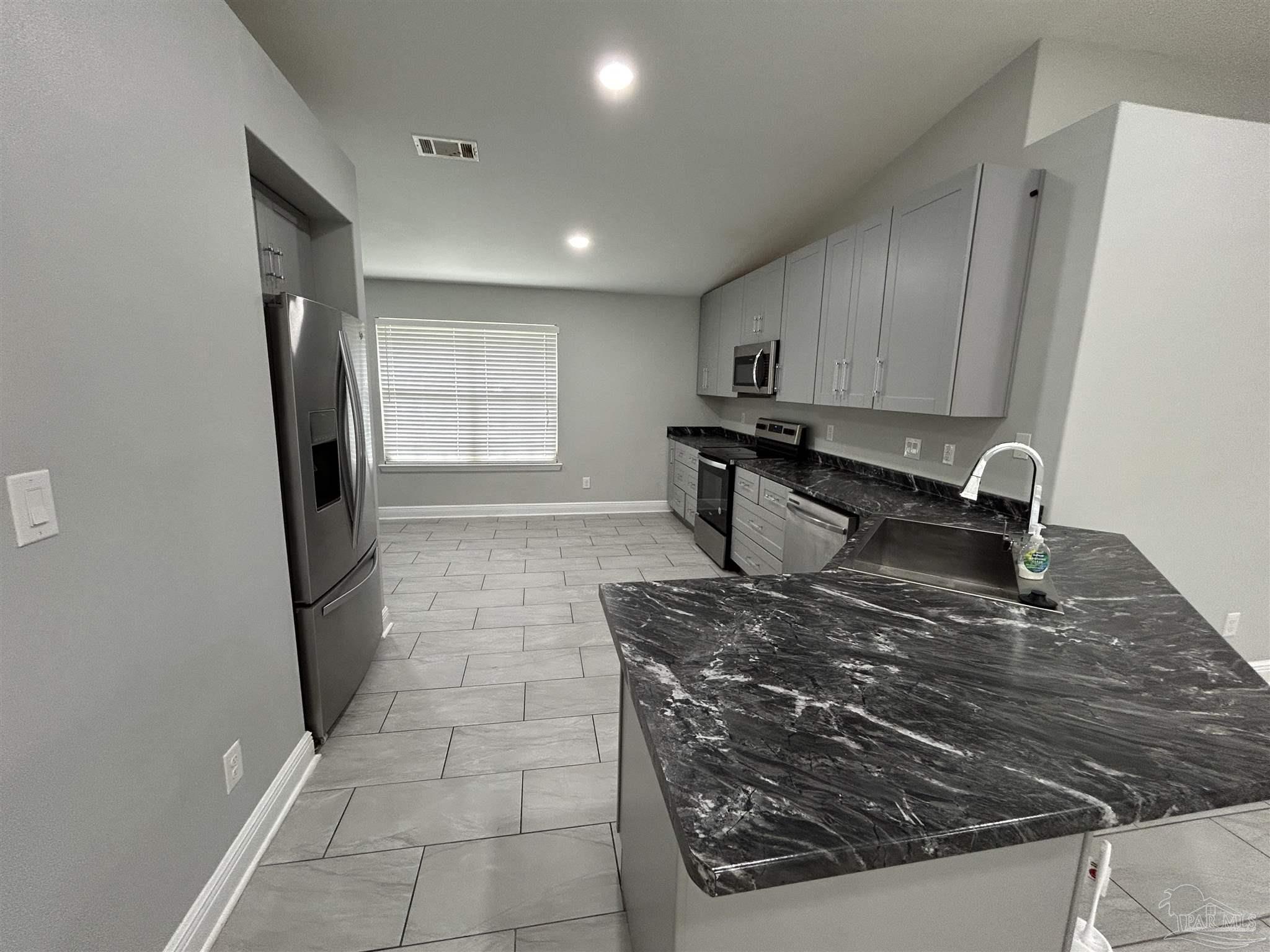 3405 Wasatch Range Loop Pensacola, FL 32526 - Photo 3 of 13 a kitchen with kitchen island granite countertop a stove sink and cabinets