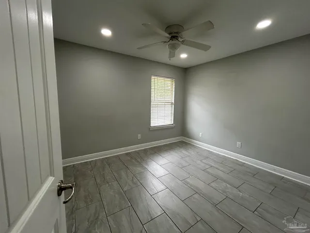 an empty room with windows and fan