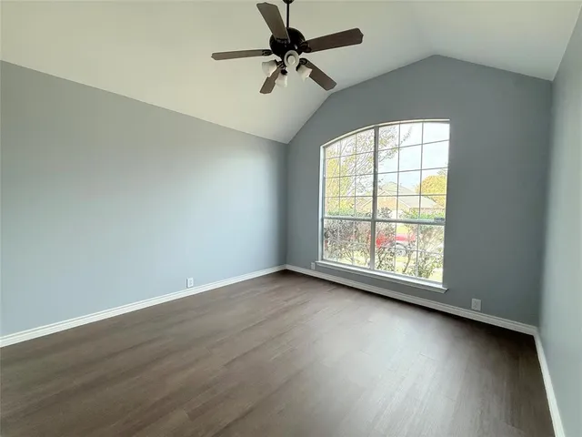 an empty room with wooden floor fan and windows