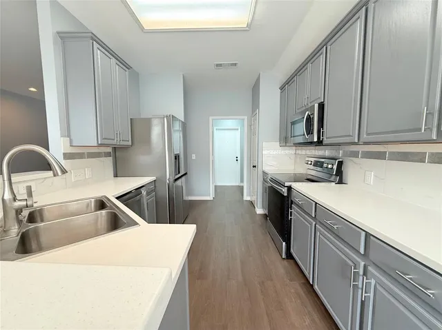 a kitchen with kitchen island granite countertop a sink a counter top space stainless steel appliances and cabinets