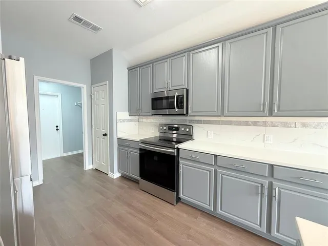a kitchen with granite countertop white cabinets and stainless steel appliances