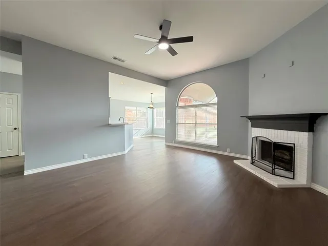 an empty room with windows fireplace and wooden floor