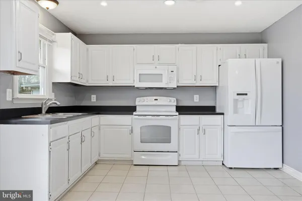 a kitchen with white cabinets and white appliances