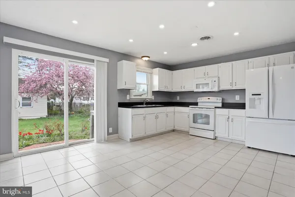a kitchen with granite countertop white cabinets and white stainless steel appliances