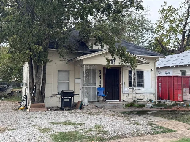 a view of a house with a large tree and wooden fence