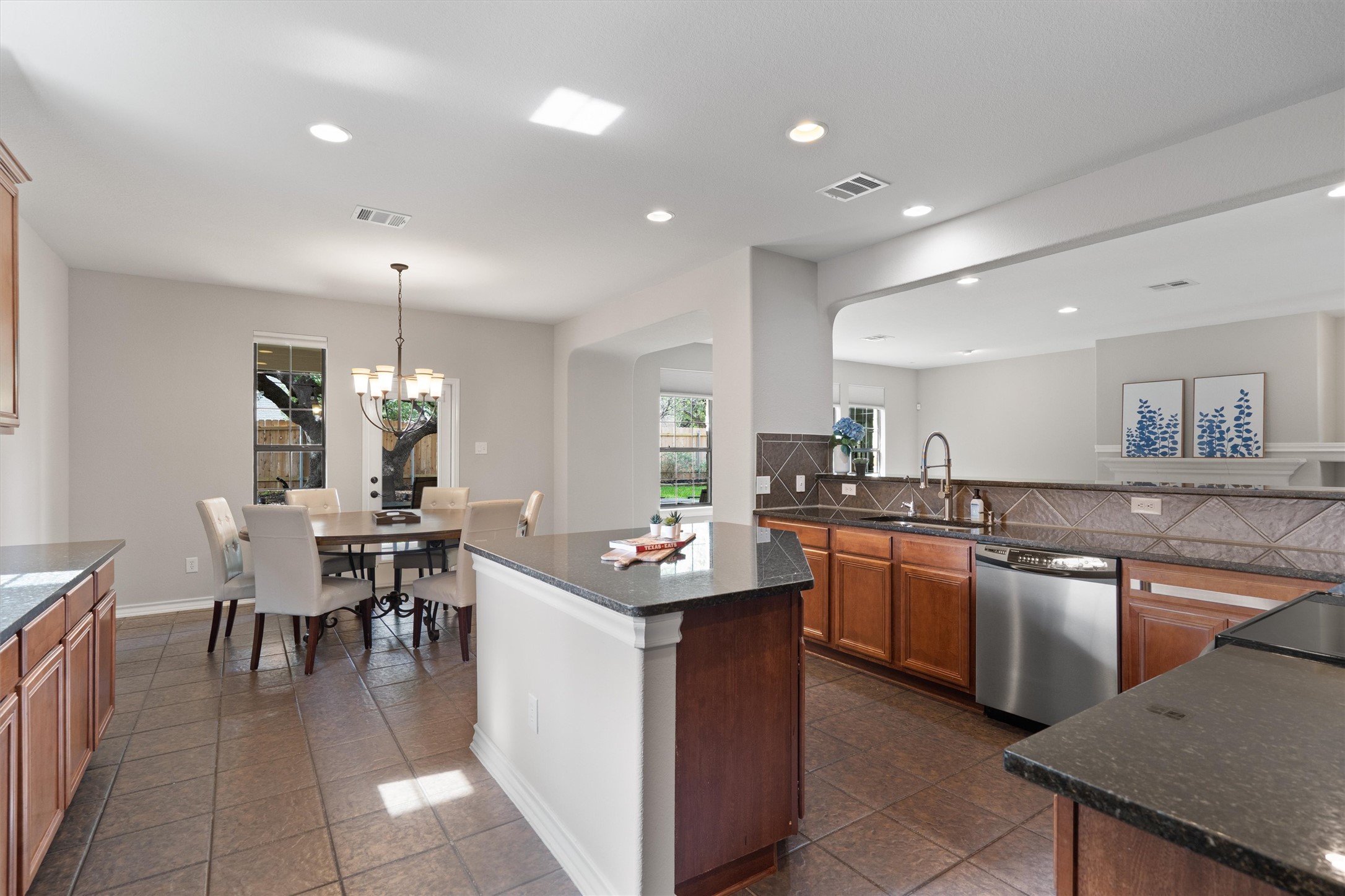 101 Breakaway Road Cedar Park, TX 78613 - Photo 12 of 37 Kitchen featuring decorative backsplash, stainless steel dishwasher, a center island, dark stone counters, and wood finish cabinetry