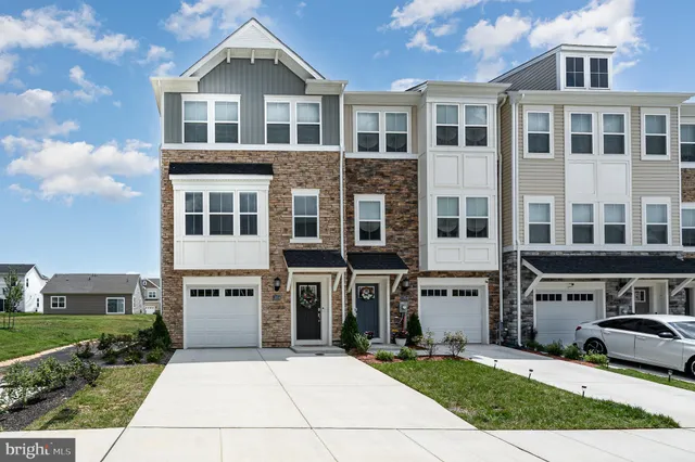 a front view of a building with a garden and parking space