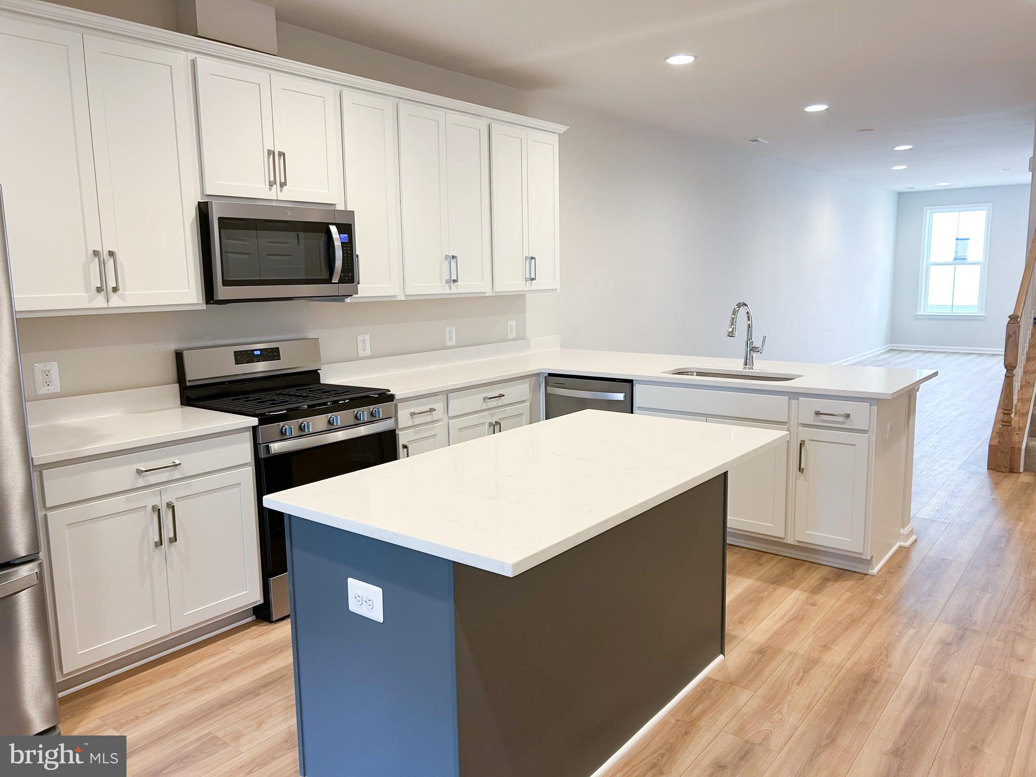 119 Heirloom Way Winchester, VA 22603 - Photo 6 of 26 a kitchen with stainless steel appliances a sink dishwasher stove and white cabinets with wooden floor