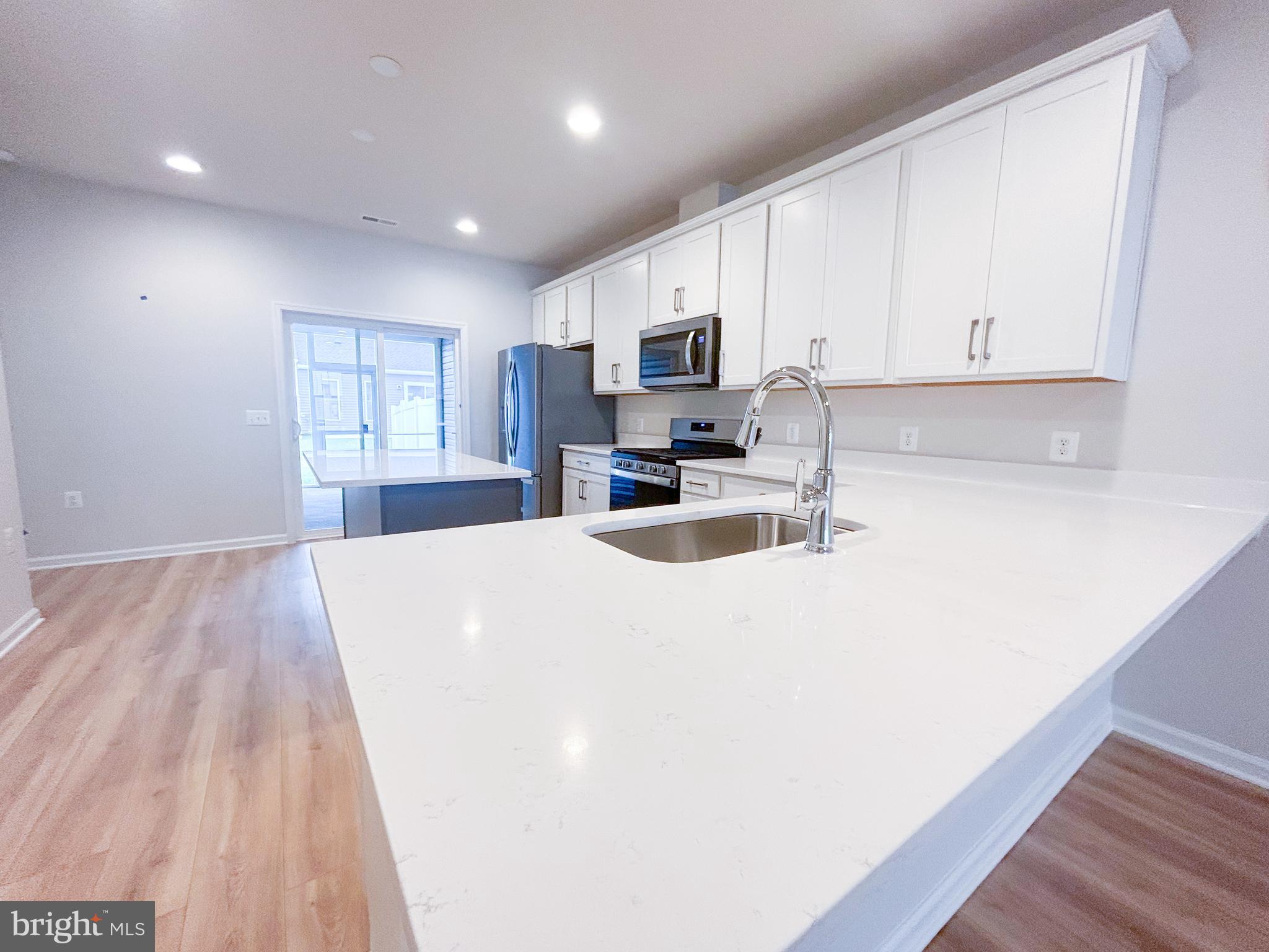119 Heirloom Way Winchester, VA 22603 - Photo 9 of 26 a large white kitchen with kitchen island a sink wooden floor and white appliances