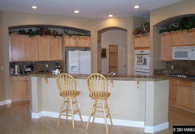 5614 North White Sands Road Reno, NV 89511 - Photo 5 of 9 a kitchen with stainless steel appliances granite countertop a stove a sink a refrigerator with a dining table and chairs