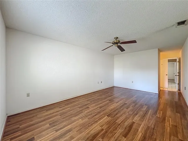 a view of a room with wooden floor and a ceiling fan