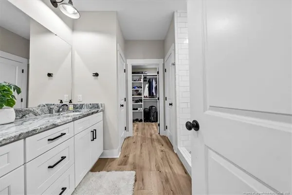 a spacious bathroom with a granite countertop sink a mirror and shower