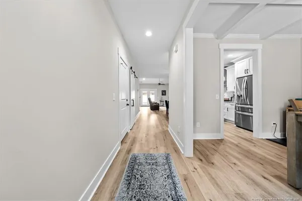 a view of a hallway with wooden floor and a living room