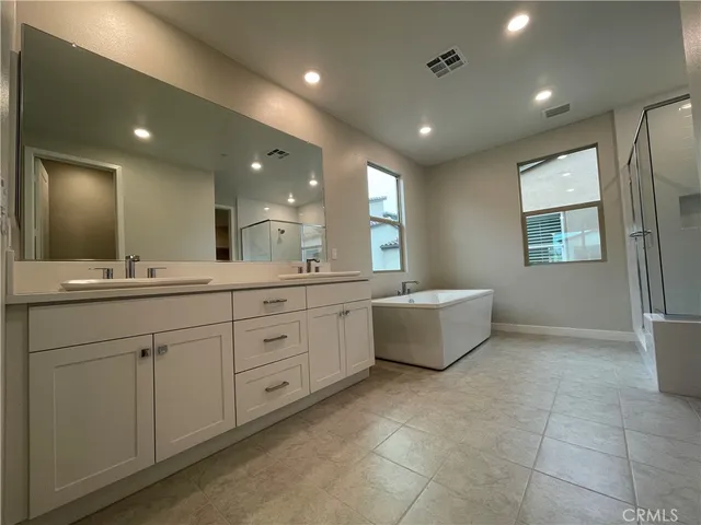 a spacious bathroom with a double vanity sink mirror and bathtub