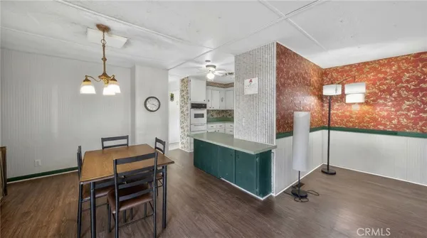 a open kitchen with stainless steel appliances granite countertop a stove a refrigerator a oven and a dining table with wooden floor