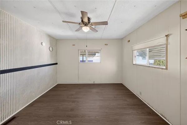 an empty room with wooden floor fan and windows