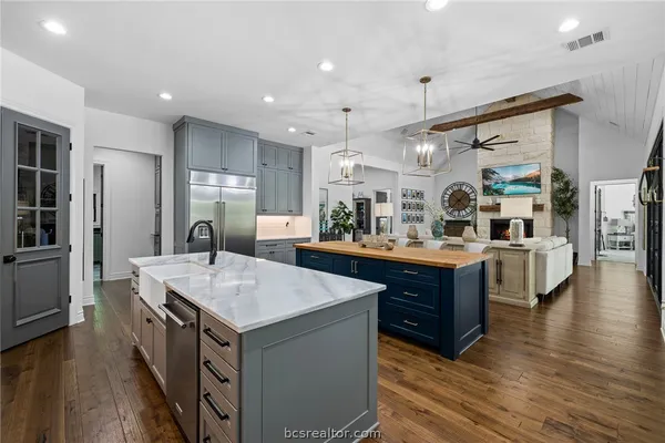 a kitchen with stainless steel appliances kitchen island granite countertop a stove a sink a refrigerator and a dining table with wooden floor