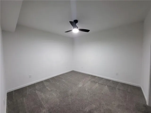 an empty room with ceiling fan and window