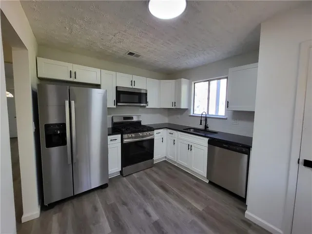 a kitchen with granite countertop a refrigerator stove a sink and dishwasher