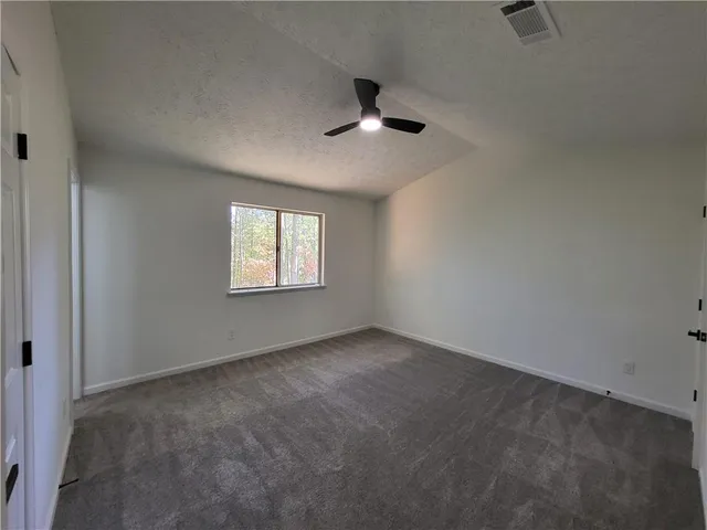 an empty room with windows and fan