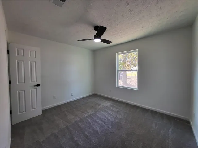 an empty room with windows and fan