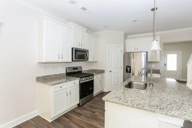 a kitchen with stainless steel appliances granite countertop a sink stove and refrigerator